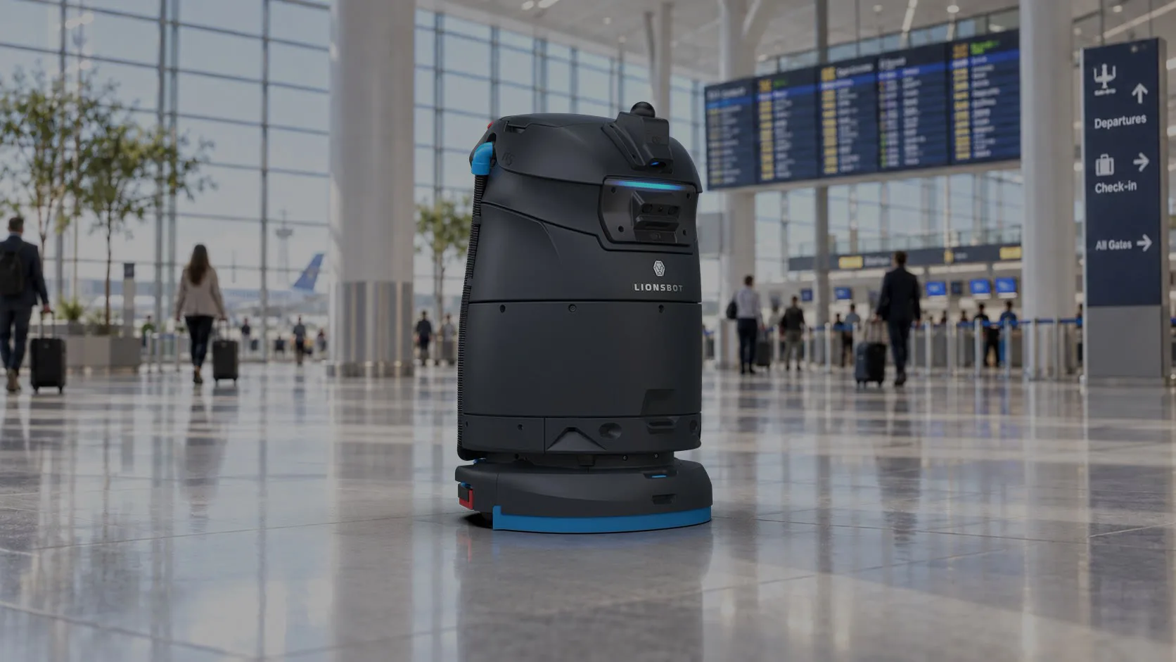 A LionsBot R5 autonomous floor scrubber cleaning an airport terminal floor, with departure boards and travellers with luggage behind it