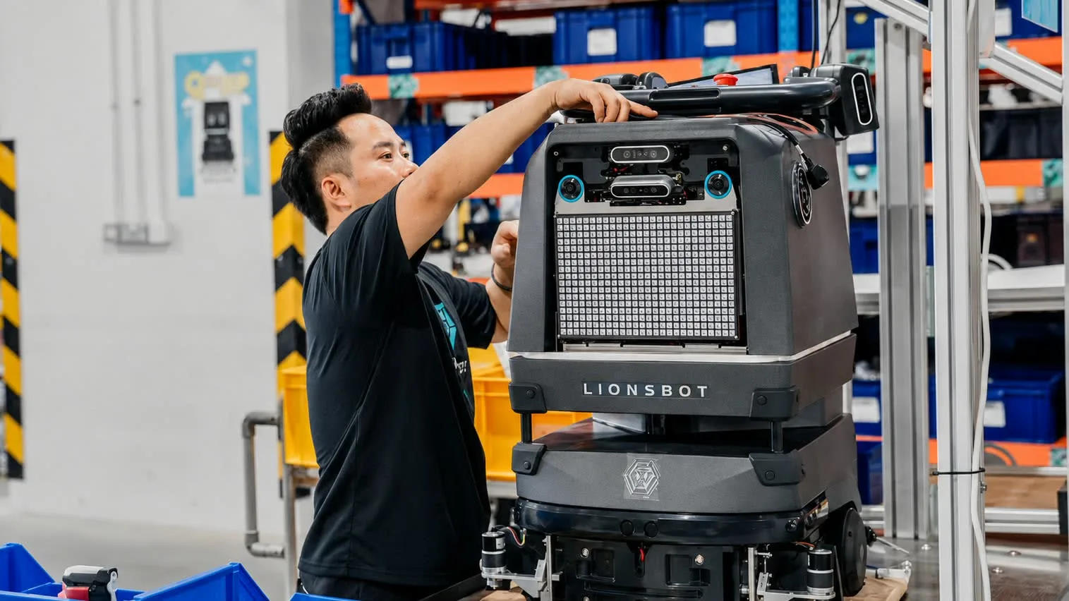 A LionsBot technician assembling an R5 autonomous floor scrubber on the engineering floor in Singapore