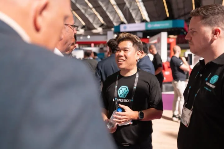 A LionsBot team member in a branded T-shirt talking with visitors on the stand at Interclean Amsterdam