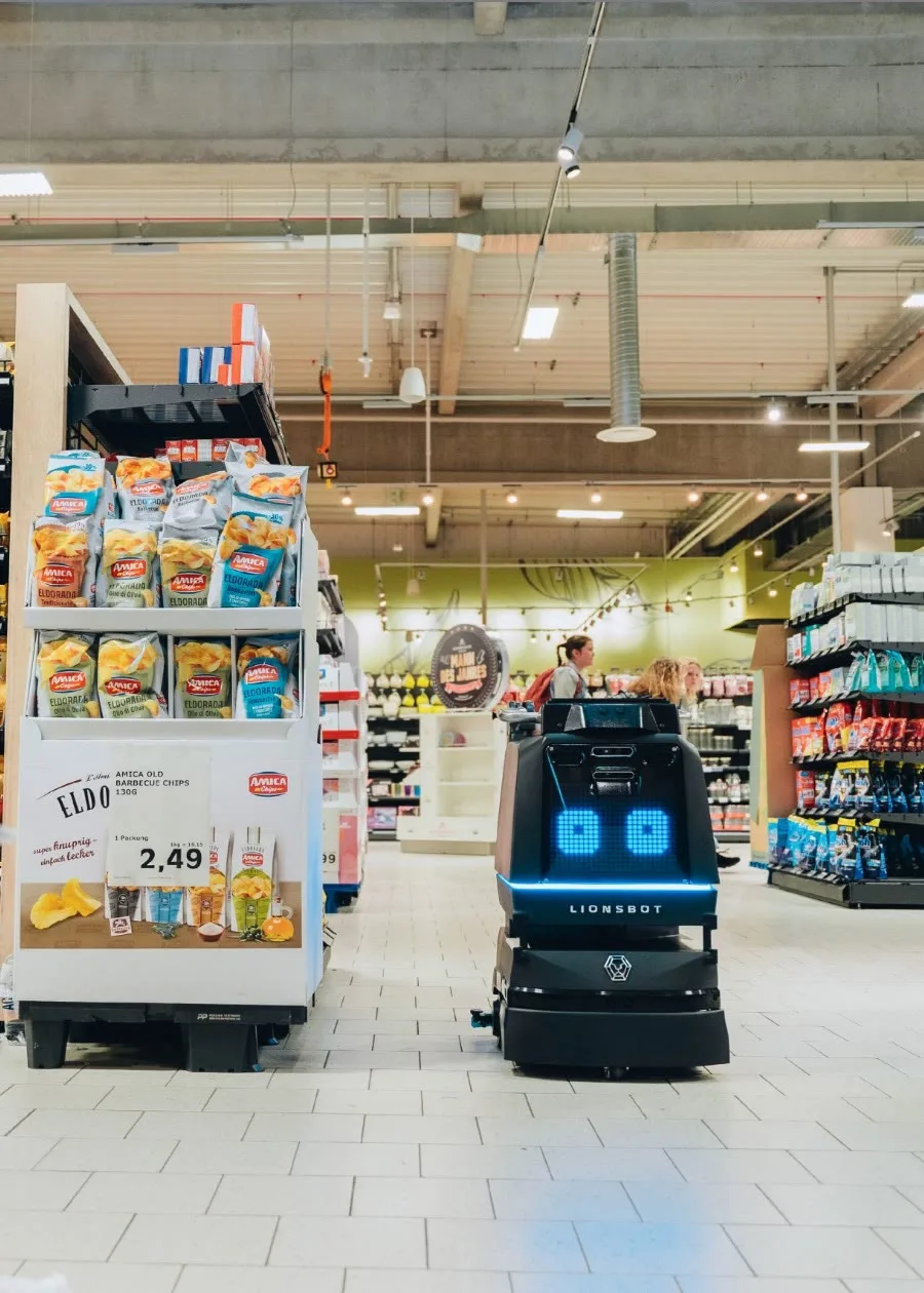 A LionsBot R3 Scrub Pro cleaning a supermarket aisle while the store is open