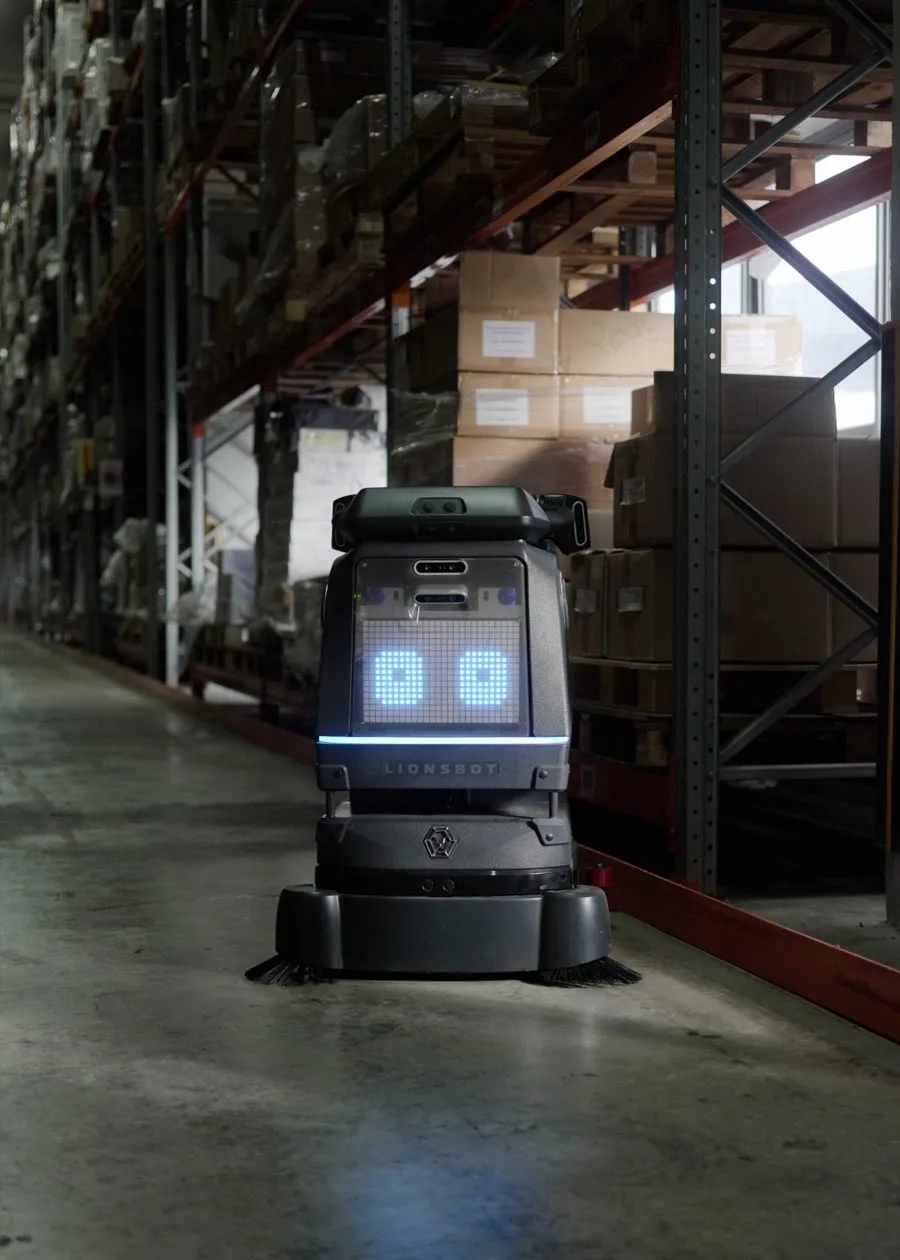 A LionsBot R3 Scrub Pro cleaning a narrow warehouse aisle between pallet racking