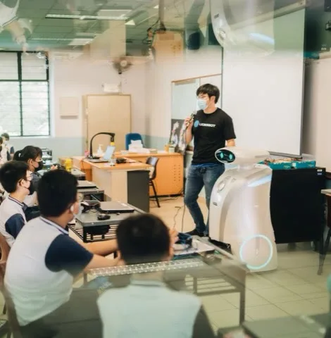 A LionsBot team member presenting a robot to a classroom of primary school students
