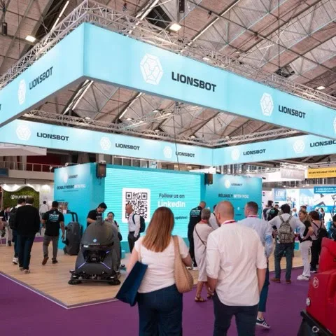 Visitors walking through the LionsBot stand at Interclean Amsterdam 2024 under a large branded canopy