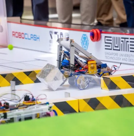 A student-built competition robot pushing a block across the RoboClash arena