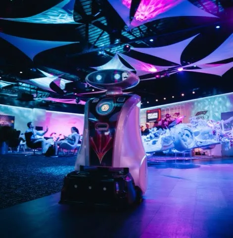 A LionsBot robot on an event floor under purple and blue stage lighting at a Formula 1 event