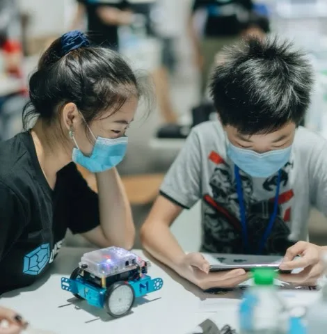 Two children working with a small programmable robot at a Code in the Community session