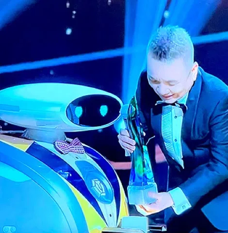 A LionsBot robot wearing a bow tie handing a trophy to a presenter on stage at the Mediacorp Star Awards